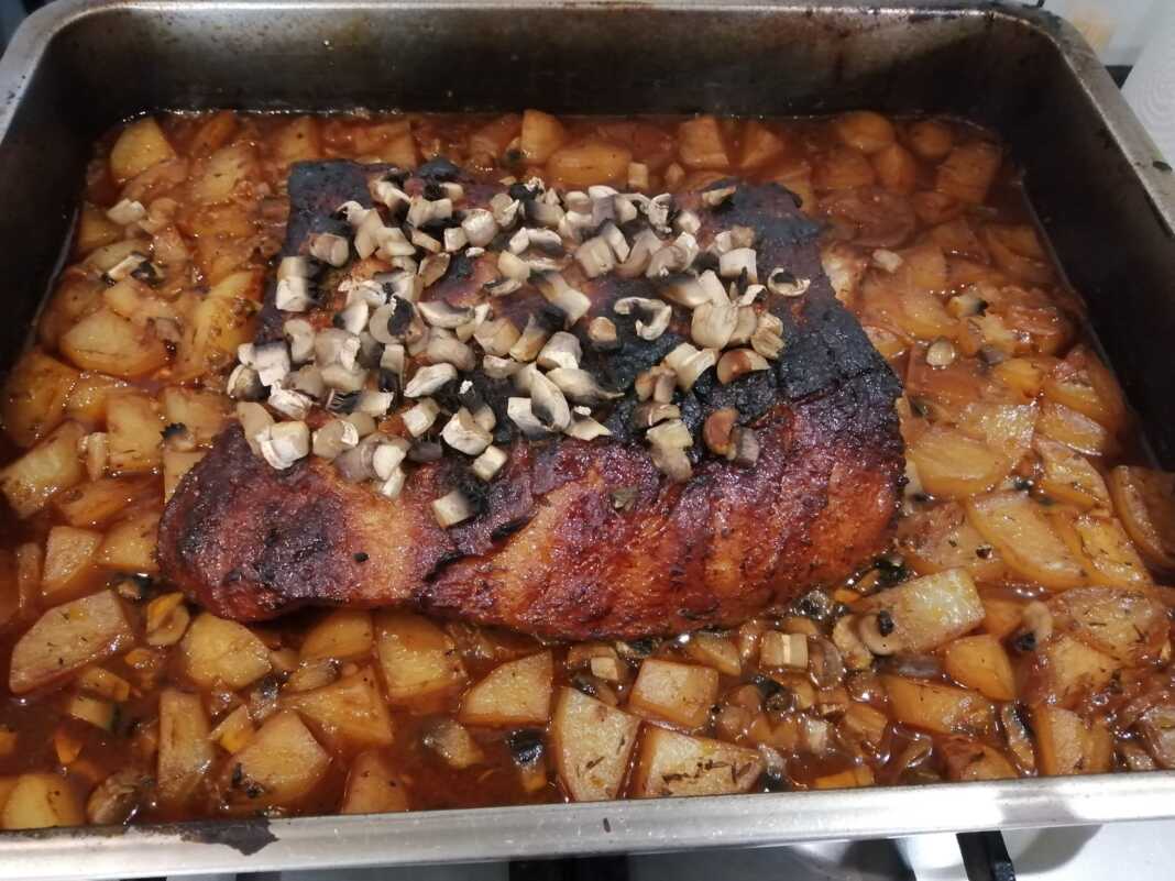 xoirinoPatates Χοιρινό μπούτι με πατάτες σε ταψί, ψημένο και έτοιμο να σερβιριστεί.