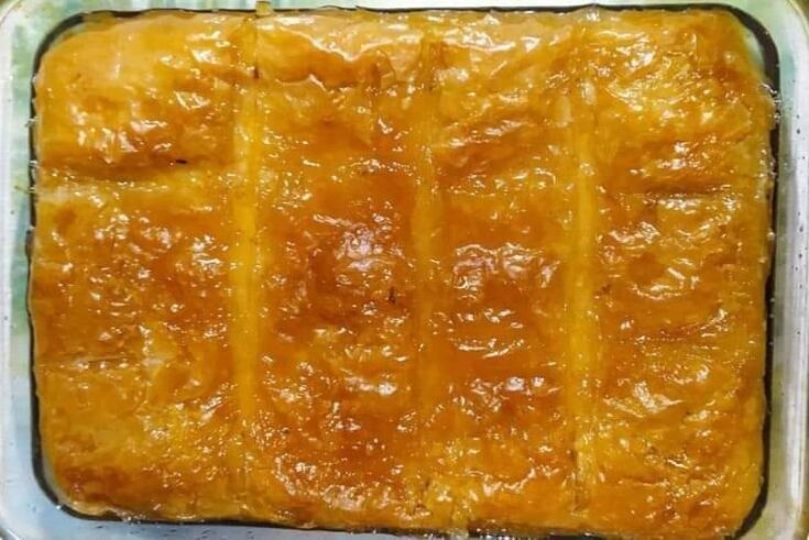 Πιάτο με χρυσαφένιο, τραγανό γαλακτομπούρεκο σε πιάτο, που δείχνει τις πολλές στρώσεις φύλλου κρούστας και την πλούσια, κρεμώδη γέμιση σιμιγδαλιούχουνκιάρ μπεγιεντί, που δείχνει μια πλούσια στρώση κρεμώδους πουρέ μελιτζάνας και από πάνω κομμάτια κοκκινιστού μοσχαριού με δεμένη σάλτσα