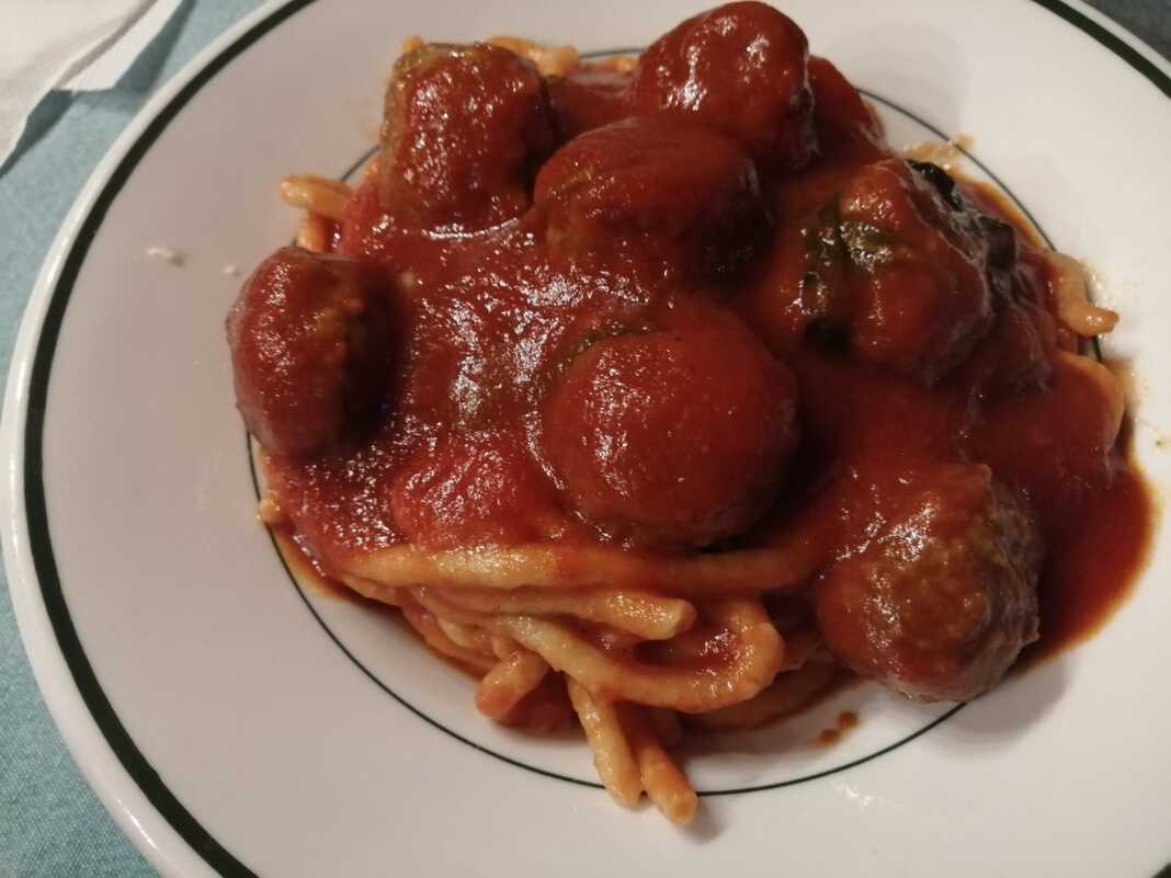 Ένα πιάτο με μακαρόνια και κεφτεδάκια κοκκινιστά, περιχυμένα με κόκκινη σάλτσα.