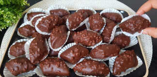 Ένα ταψί με λαδόκολλα γεμάτο με σκουρόχρωμα, σοκολατένια μπισκότα, μερικά από τα οποία είναι ήδη βουτηγμένα σε λιωμένη σοκολάτα και πασπαλισμένα με αμύγδαλα.