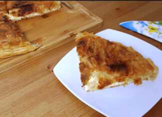 Μια χρυσαφένια, φρεσκοψημένη τυρόπιτα με εμφανή στρώματα φύλλου, κομμένη σε τετράγωνα κομμάτια, που αναδεικνύει την τραγανή της υφή.