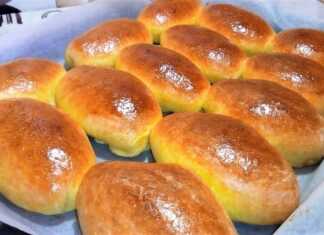 Σειρά από χρυσαφένια, φουσκωτά μηλοψωμάκια πάνω σε ταψί με λαδόκολλα, αλειμμένα με αυγό για λάμψη