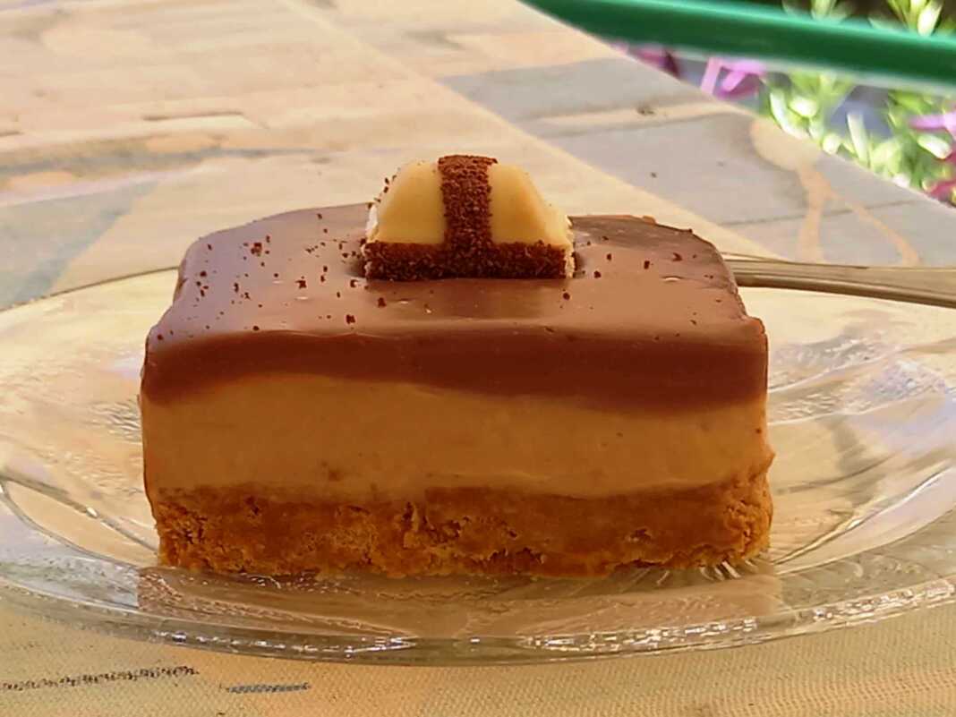 Τεμάχιο cheesecake με Kinder σοκολάτα, με στρώσεις μπισκότου, κρέμας και γκανάς, διακοσμημένο με Kinder Bueno.