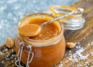 Ρευστή χρυσαφένια καραμέλα που ρέει από ένα κουτάλι μέσα σε γυάλινο βαζάκι, αναδεικνύοντας τη λεία και γυαλιστερή της υφή