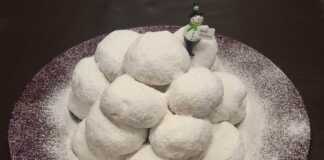 Πιατέλα με χιονισμένους Κουραμπιέδες πασπαλισμένους με άχνη, με εμφανή τα χοντροκομμένα αμύγδαλα.