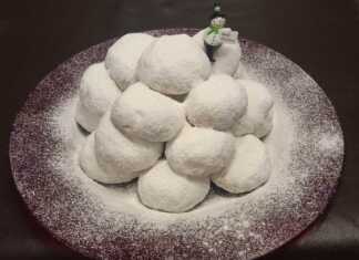 Πιατέλα με χιονισμένους Κουραμπιέδες πασπαλισμένους με άχνη, με εμφανή τα χοντροκομμένα αμύγδαλα.