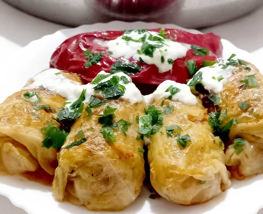 Μια πιατέλα με ζεστούς, λαχταριστούς λαχανοντολμάδες, περιχυμένους με δροσερή σως γιαουρτιού και πασπαλισμένους με φρέσκο άνηθο.