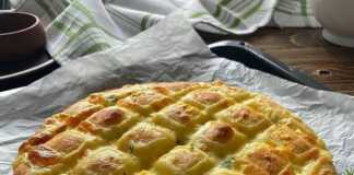 Σπιτικό ψωμί με τυρί και μυρωδικά, με χρυσαφένια κρούστα και εμφανείς τις τομές γεμισμένες με τυρί.