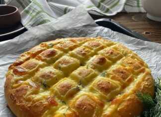 Σπιτικό ψωμί με τυρί και μυρωδικά, με χρυσαφένια κρούστα και εμφανείς τις τομές γεμισμένες με τυρί.