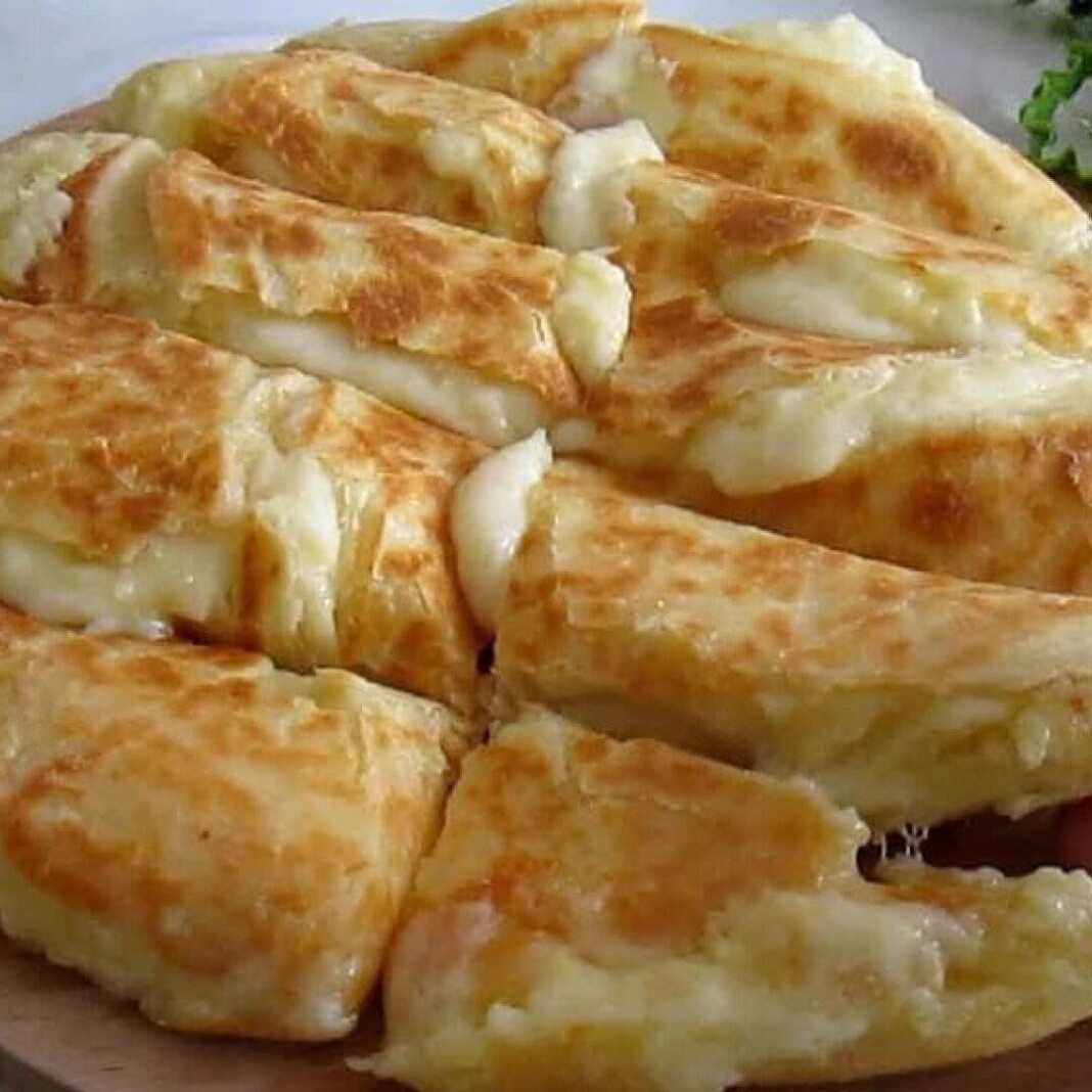 Χρυσαφένιο τυρόψωμο πατάτας στο τηγάνι με λιωμένη μοτσαρέλα να ξεχειλίζει από το εσωτερικό του