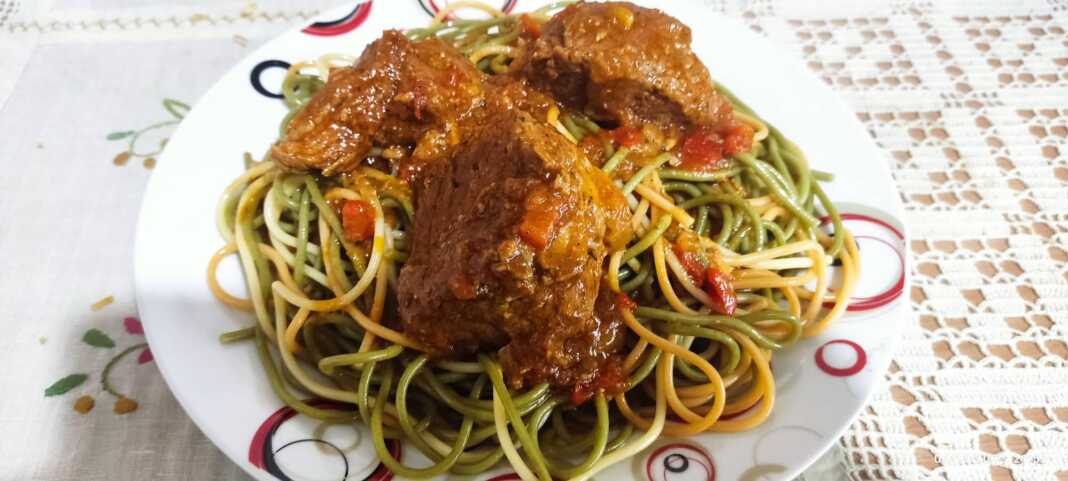 Φωτογραφία με σπαγγέτι τρικολόρε σερβιρισμένο με κομμάτια μοσχαριού και κόκκινη σάλτσα.