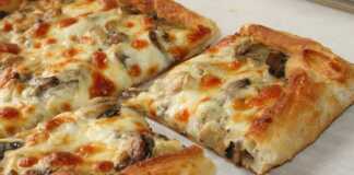 Ζουμερή πίτσα σφολιάτας με λιωμένα τυριά, μανιτάρια και ζαμπόν, φρεσκοψημένη.