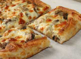 Ζουμερή πίτσα σφολιάτας με λιωμένα τυριά, μανιτάρια και ζαμπόν, φρεσκοψημένη.