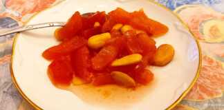 Γλυκό του κουταλιού κυδώνι σε πιατιάκι , με κομμάτια αμύγδαλου και κλωνάρι αρμπαρόριζα.