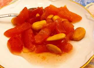 Γλυκό του κουταλιού κυδώνι σε πιατιάκι , με κομμάτια αμύγδαλου και κλωνάρι αρμπαρόριζα.