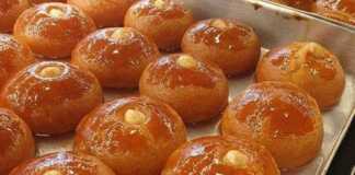 Χρυσαφένια σεκέρ παρέ σε ένα ταψί, σιροπιασμένα και με ένα φουντούκι στην κορυφή.