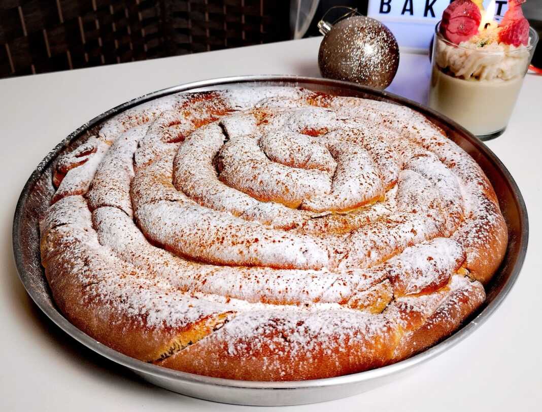 Μεγάλη στρογγυλή νηστίσιμη ταχινόπιτα ταψιού, ψημένη και πασπαλισμένη με άχνη ζάχαρη και κανέλα.