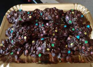 Μικροί σωροί από αλατισμένα φιστίκια καλυμμένα με σκούρα και λευκή σοκολάτα, τοποθετημένα σε λαδόκολλα, με χρωματιστά κουφετάκια για διακόσμηση.