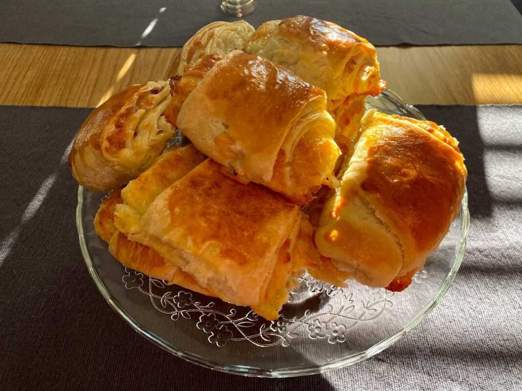 Ένα ταψί γεμάτο χρυσαφένια, φουσκωτά ζαμπονοτυροπιτάκια κομμένα σε ροδέλες, έτοιμα να σερβιριστούν.