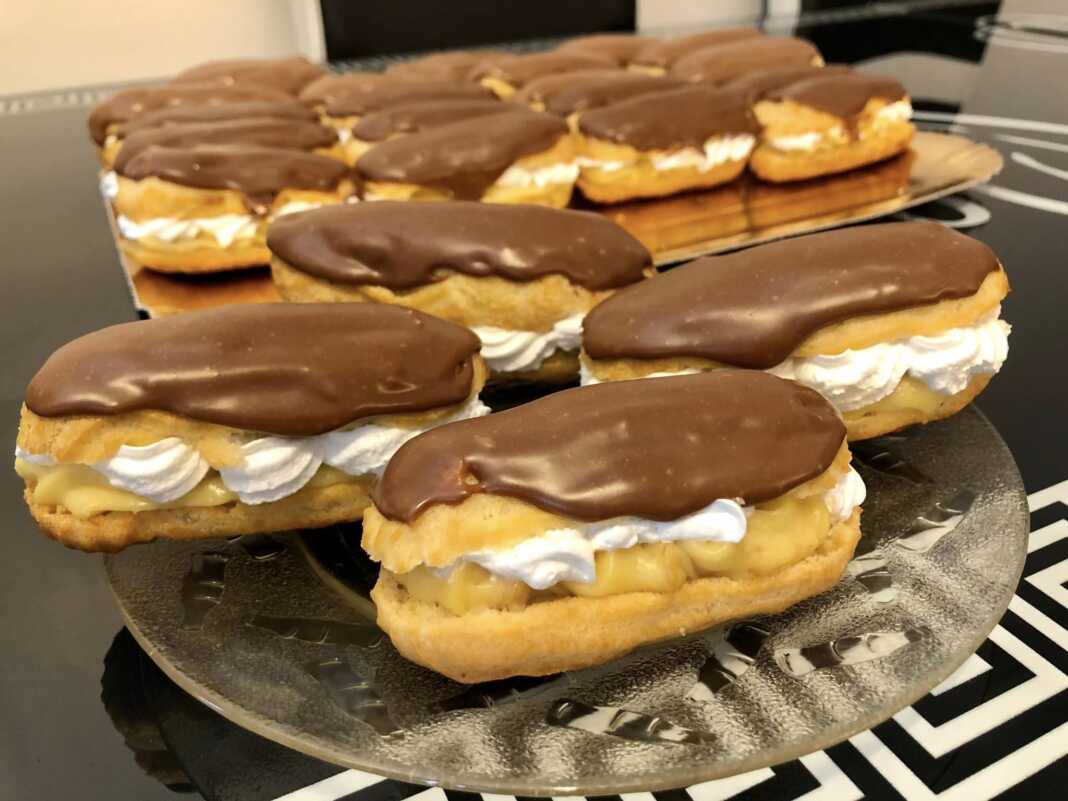 Λαχταριστά εκλέρ με κρέμα βανίλιας και γλάσο σοκολάτας σε γιαλυνη επιφάνεια.