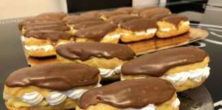 Λαχταριστά εκλέρ με κρέμα βανίλιας και γλάσο σοκολάτας σε γιαλυνη επιφάνεια.