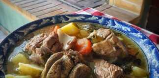 Αχνιστή γιδόσουπα σε βαθύ πιάτο με χοντροκομμένα λαχανικά και ζουμερό κρέας σερβιρισμένη με λεμόνι