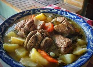 Αχνιστή γιδόσουπα σε βαθύ πιάτο με χοντροκομμένα λαχανικά και ζουμερό κρέας σερβιρισμένη με λεμόνι