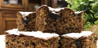 Ένα κομμάτι κέικ με καρύδια και μαρμελάδα δαμάσκηνο πασπαλισμένο με ζάχαρη άχνη.