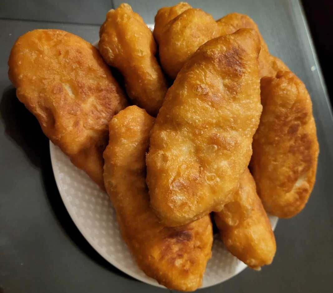 Τηγανισμένα πιροσκί με χρυσαφένια κρούστα, γεμιστά με πουρέ πατάτας, σε ένα πιάτο.