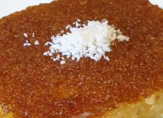 Ένα κομμάτι σιροπιαστό ραβανί με γιαούρτι, πασπαλισμένο με λίγο τριμμένο λεμόνι, σερβιρισμένο σε πιάτο.