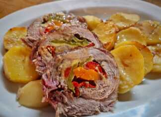 Χοιρινό ρολό κομμένο σε φέτες που αποκαλύπτουν τη γέμιση από λαχανικά και λιωμένο τυρί σερβιρισμένο με πατάτες φούρνου