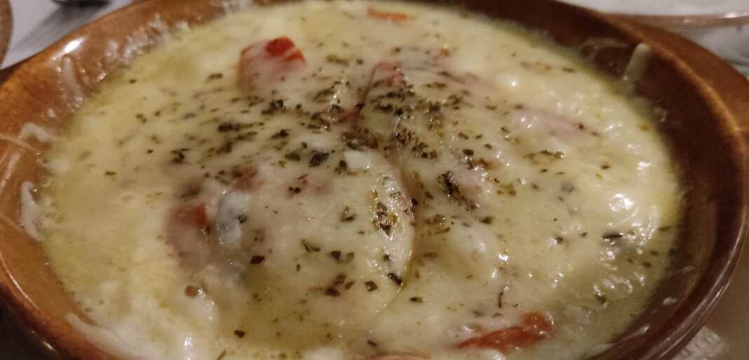 Πήλινο σκεύος με λιωμένο Τυρένιο Μπουγιουρντί με ντομάτα και ρίγανη, έτοιμο για σερβίρισμα.