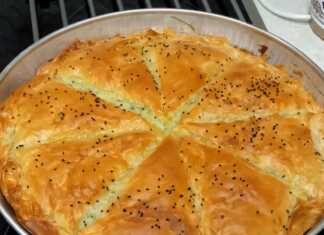 Μια χρυσαφένια νηστίσιμη πατατόπιτα χαραγμένη σε τετράγωνα κομμάτια, πασπαλισμένη με σουσάμι