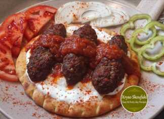 Ζουμερά κεμπάπ τοποθετημένα πάνω σε ψημένες πίτες με πλούσια κόκκινη σάλτσα ντομάτας και δροσερό στραγγιστό γιαούρτι πασπαλισμένα με σουμάκ