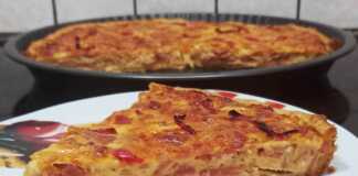 Μια ολόκληρη Quiche Lorraine (Κις Λορέν) σε φόρμα τάρτας, ψημένη, με χρυσαφένια επιφάνεια, διακοσμημένη με κόκκινη πιπεριά και αφράτη κρέμα.