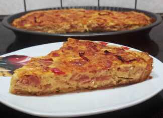 Μια ολόκληρη Quiche Lorraine (Κις Λορέν) σε φόρμα τάρτας, ψημένη, με χρυσαφένια επιφάνεια, διακοσμημένη με κόκκινη πιπεριά και αφράτη κρέμα.