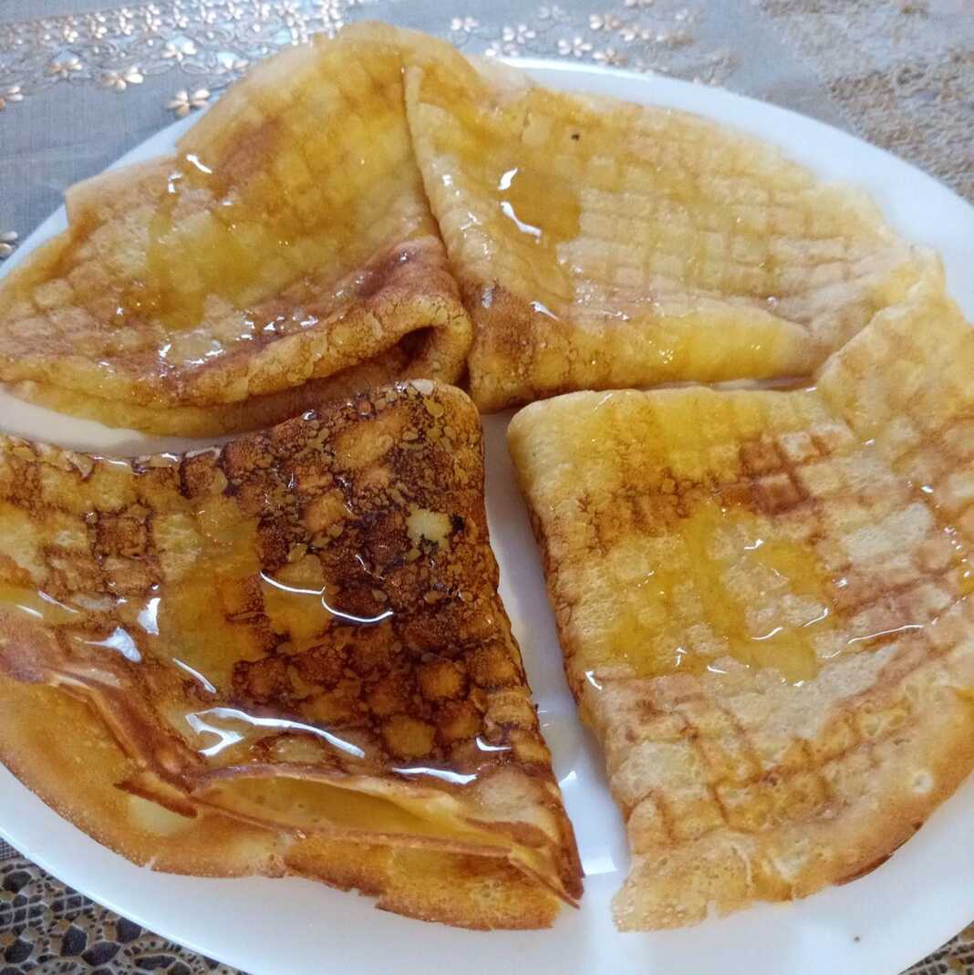 Ένα πιάτο με ζεστές, διπλωμένες κρέπες, περιχυμένες με χρυσό μέλι