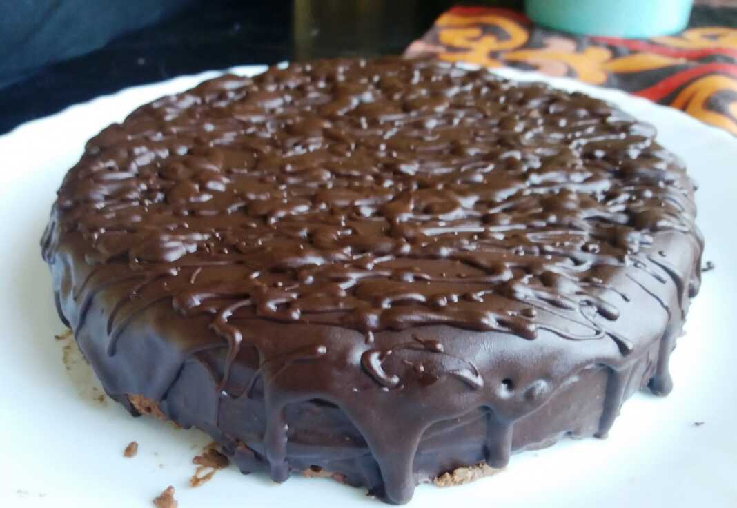 Σοκολατένιο κέικ με μπισκότα, γαρνιρισμένο με λιωμένη σοκολάτα, σερβιρισμένο σε κομμάτι.