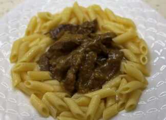 Μοσχαρίσιο Στρογκανόφ σε κρεμώδη σάλτσα με μανιτάρια, σερβιρισμένο πάνω από ζυμαρικά, γαρνιρισμένο με μαϊντανό.