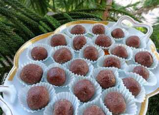 Μικρές στρογγυλές τρούφες σοκολάτας καλυμμένες με κρυσταλλική ζάχαρη τοποθετημένες σε διακοσμητικά χαρτάκια