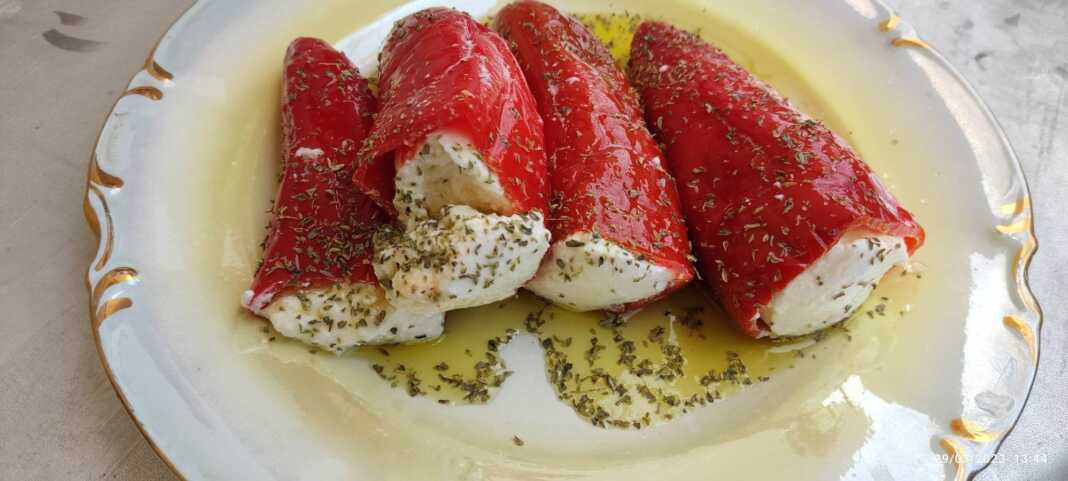 Piperies Florinhs Gemistes Κόκκινες πιπεριές Φλωρίνης γεμισμένες με λευκό μείγμα τυριών, τοποθετημένες μέσα σε γυάλινο βάζο με ελαιόλαδο και φύλλα δάφνης.