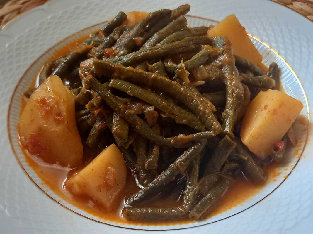 Ένα πιάτο με αχνιστά Αμπελοφάσουλα Κοκκινιστά, έτοιμα για σερβίρισμα με φέτα και ψωμί