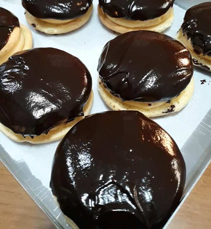 kokakia Ένα πιάτο γεμάτο με στρογγυλά κοκάκια, με τη μία πλευρά καλυμμένη με γυαλιστερό γλάσο σοκολάτας, που δείχνουν την κρεμώδη γέμιση στο εσωτερικό.