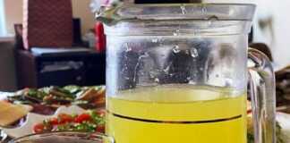 Ένα γυάλινο δοχείο γεμάτο σπιτική λεμονάδα με φέτες λεμονιού και κλωναράκια μέντας, έτοιμο για σερβίρισμα.