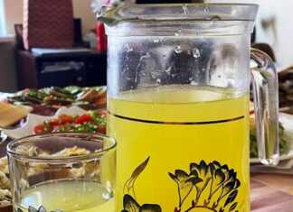 Ένα γυάλινο δοχείο γεμάτο σπιτική λεμονάδα με φέτες λεμονιού και κλωναράκια μέντας, έτοιμο για σερβίρισμα.