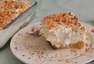 Ένα κομμάτι εκμέκ τσουρέκι σε ένα λευκό πιάτο, που δείχνει μια στρώση σιροπιασμένου τσουρεκιού, μια στρώση κίτρινης κρέμας ζαχαροπλαστικής και μια στρώση λευκής σαντιγί, πασπαλισμένο με αμύγδαλα φιλέ και λίγη κανέλα.