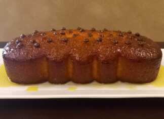 Αφράτο σιροπιαστό κέικ πορτοκάλι, κομμένο σε φέτες, με γλάσο ζάχαρης και φλούδες πορτοκαλιού.