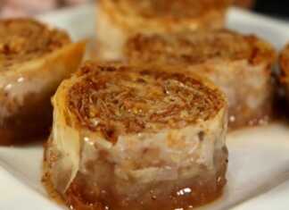 Ένα ταψί με χρυσαφένια ρολάκια μπακλαβά σιροπιασμένα, τοποθετημένα το ένα δίπλα στο άλλο.