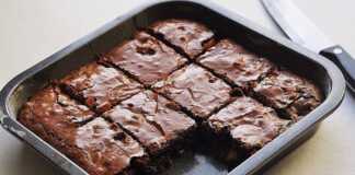 Τετράγωνα κομμάτια ζουμερού, σοκολατένιου μπράουνι με μπανάνα, τοποθετημένα σε μια πιατέλα, με τη χαρακτηριστική τους σκούρα όψη.