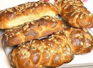 Καλοσχηματισμένες πλεξούδες τσουρεκιού με γυαλιστερή όψη, πασπαλισμένες με φιλέ αμυγδάλου, που δείχνουν την ελαστική τους υφή